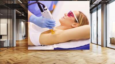 Woman receiving underarm laser hair removal at a beauty center. Wall mural