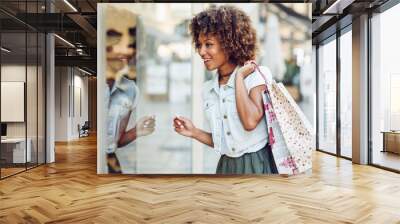 Young black woman, afro hairstyle, looking at a shop window Wall mural