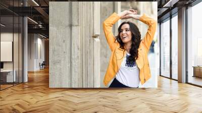 Young brunette woman smiling in urban background. Wall mural