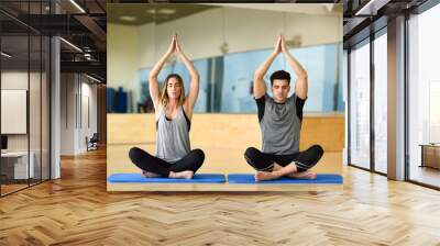 Young woman and man practicing yoga indoors Wall mural