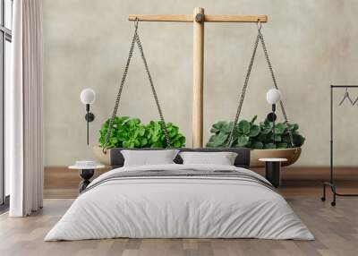 A balance scale displaying two bowls of fresh green plants, symbolizing harmony and comparison in nature. Wall mural