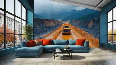 A heavy dump truck navigates a rugged terrain, transporting materials across a construction site surrounded by mountains. Wall mural