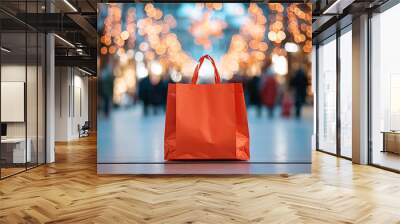 A vibrant red shopping bag stands out against a blurred background of glowing festive lights and busy shoppers. Wall mural