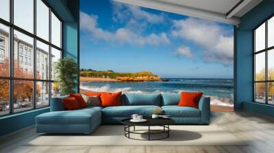 A curved orange sand beach with white waves and dramatic clouds in the blue sky Wall mural