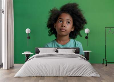 Portrait of lovely young african american girl look empty space wear shirt isolated on green color background Wall mural