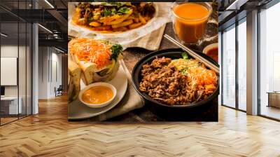 Vietnamese food - Korean style beef bulgogi bowl with ham headcheese BBQ pork sandwich, Kimchi fries, and thai iced tea on the wooden table Wall mural