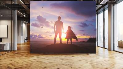 Super Son holding hand of fatheroutdoors on background sunset. Father holiday Wall mural