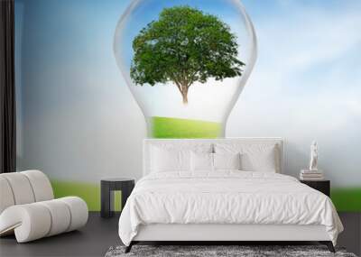 Tree in electric bulb on grassland. Eco energy concept. Wall mural