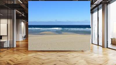 Beach with golden sand and blue sea with waves and foam. Clear sky, sunny day. Galicia, Spain. Wall mural