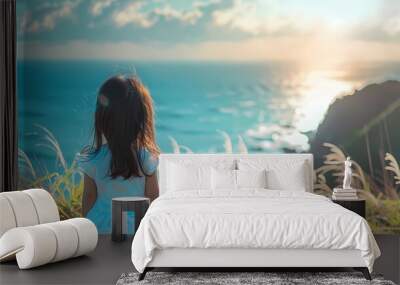 Back view an Asian little girl is looking at the sea on the edge of the cliff, sea breeze is blowing and the sun is shining, Generative AI illustrations. Wall mural