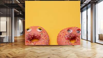 Two glazed pink donuts isolated with funny faces. Wall mural