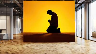 Christian prayer. Man on his knees praying on sunset background. Kneeling prayer to God. Worship and praise. Wall mural