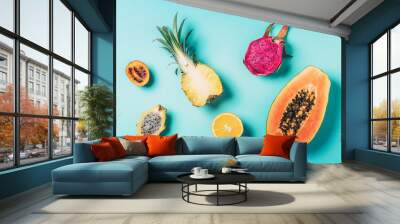 Creative layout made of exotic fruits - papaya, pineapple, dragon fruit, pitahaya, tamarillo fruit on blue background. Flat lay. Top view. Copy space. Summer food, tropical fruits concept. Vegan Wall mural