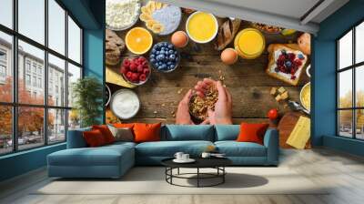 Girl cooking breakfast - granola with yogurt, fruits, berries, milk, yogurt, juice, cheese. Top view, copy space. Clean eating, dieting, detox, vegetarian food concept Wall mural