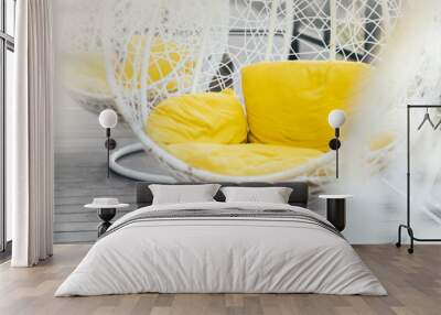 Hanging wicker chair, yellow cushions in minimalistic style outdoor interior. Demonstrating trendy Color of the Year 2021. Illuminating Yellow and Ultimate Gray. Duotone. Depression treatment. Banner Wall mural