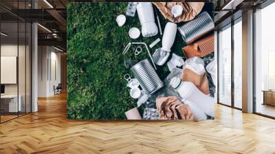 Plastic waste, food packaging, trash collection on green moss background after picnic in forest. Plastic free. Top view. Copy space. Recycling plastic. Environmental pollution, ecology concept. Wall mural