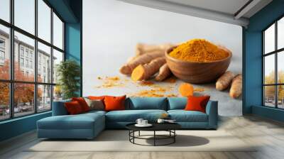 Turmeric powder in wooden bowl and fresh turmeric root on grey concrete background. Banner with copy space Wall mural