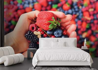 Woman hands holding organic fresh berries against the background of strawberry, blueberry, blackberries, currant, mint leaves. Top view. Summer food. Vegan, vegetarian and clean eating concept. Wall mural