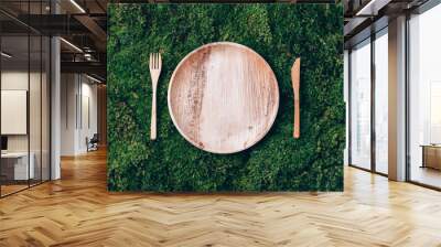 Wooden disposable tableware from natural materials, wooden spoon, fork on green moss background. Eco-friendly sustainable lifestyle. Zero waste picnic Wall mural