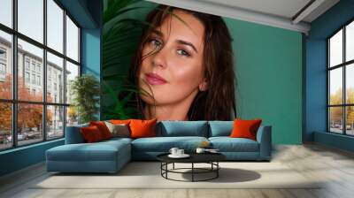 Young girl with wet hair, natural make up between tropical palm leaves on green background. Banner, copy space. Skin care, pure beauty, body treatment, fashion, cosmetics concept. Wall mural