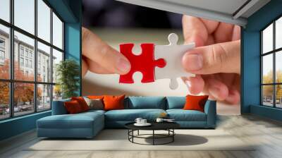 hand connecting two puzzle pieces on table background Wall mural