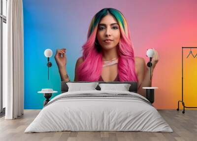 A woman with vibrant pink hair strikes poses amidst colorful rainbow lighting in a professional studio setting. Wall mural