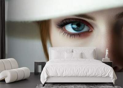 Close-up portrait of a woman wearing a stylish hat, showcasing captivating blue eyes and an elegant look. Wall mural