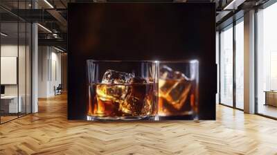 Elegant glasses filled with whiskey and ice, showcasing rich amber tones against a dark background, perfect for beverage lovers. Wall mural