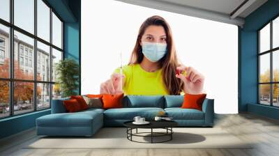 Young woman looking at the camera while holding a syringe in one hand and a red pill on the other Wall mural