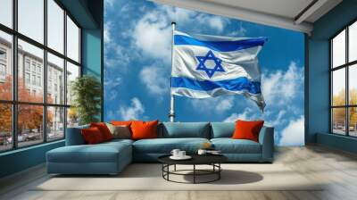 Israeli flag with Star of David waving against a bright blue sky with white clouds, symbolizing national pride and heritage. Wall mural