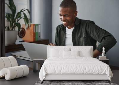 I shouldve been working from home all along. Shot of a young businessman using his laptop while working from home. Wall mural