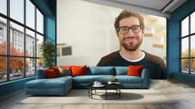 Shot of a young entrepreneur using a mobile phone in his office. Portrait of a confident young entrepreneur standing in his office. Wall mural