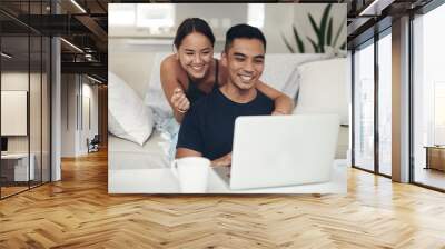 They found something interesting online. Shot of a young couple using a laptop together at home. Wall mural