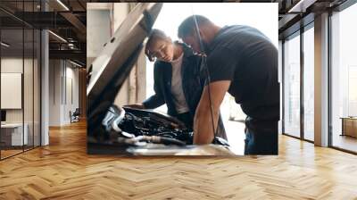 Trying to identify the source of the problem. two mechanics working together on a car in an auto repair shop. Wall mural