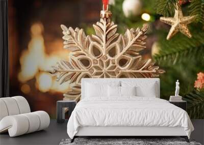 Elegant gold snowflake ornament hanging on a festive Christmas tree with a glowing fireplace in the background. Ideal for holiday greeting cards or seasonal social media posts. Wall mural