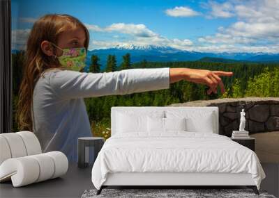 Young girl in mask pointing in the mountains  Wall mural