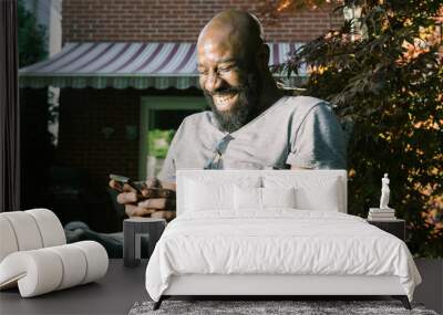 Man Laughs Reading Text Message in Garden Wall mural