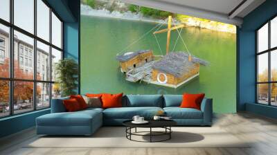 duck house made from wooden boat, floats in the emerald water of a small pond. sunny day. people car Wall mural