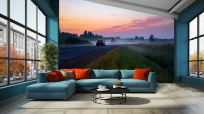 Car driving into the forest fog at sunset Wall mural