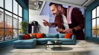 A man enjoying the aroma of his meal in a pan, cooking in his kitchen. Wall mural