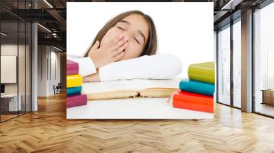 View of fatigue pretty schoolgirl covers mouth with palm, yawns as wants to sleep, being tired of studying, sits at white table, reads books. Isolated on white background Wall mural