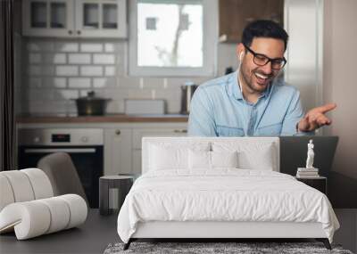 Man wearing headphones and having a video call on laptop Wall mural