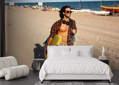 Portrait of handsome surfer with his surfboard. Young man with a surfboard on the beach Wall mural