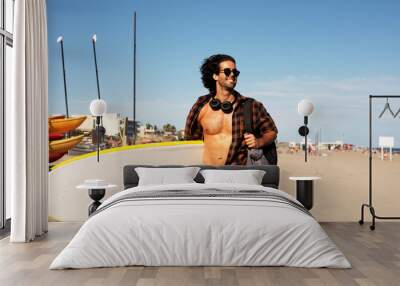 Portrait of handsome surfer with his surfboard. Young man with a surfboard on the beach Wall mural