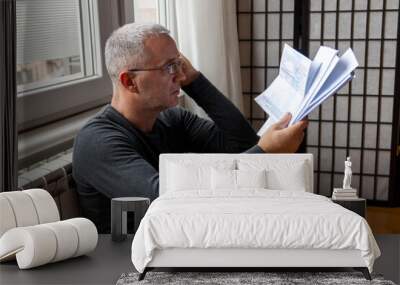 Stressed man looking at the high electricity bill because of the heat. Expensive bills. Global energy crisis concept Wall mural