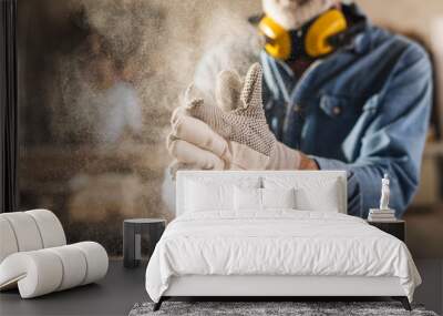 Worker is rubbing his work gloves to clean them Wall mural