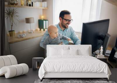 Young father working from home and babysitting his baby boy in the same time. Wall mural