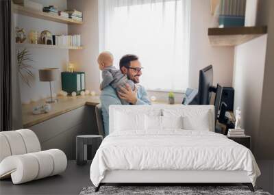 Young father working from home and babysitting. Wall mural