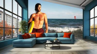 Young handsome man with his surfboard. Happy man relaxing at the beach Wall mural