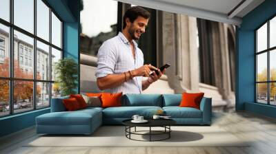 Young stylish man using the phone outdoors. Fashion happy man enjoy outdoors.. Wall mural